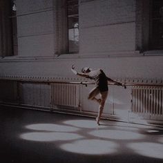 a woman is dancing in the middle of an empty room with sunlight streaming through the windows