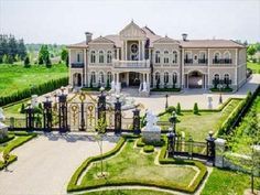 an aerial view of a large mansion in the middle of a lush green field