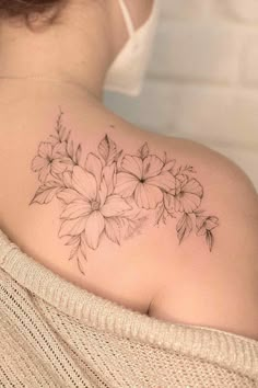 a woman's back shoulder with flowers on the upper half of her arm and behind her head