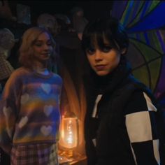 two young women standing next to each other in front of a stained glass window with hearts on it