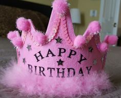 a pink birthday crown sitting on top of a bed