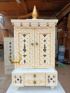 an ornate white and gold cabinet with drawers