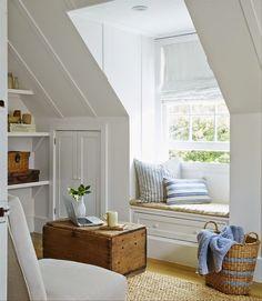 a window seat in the corner of a room with white walls and wooden flooring