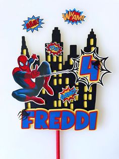 a spiderman cake topper on a stick with the word freddi in front of it