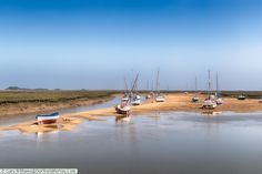 there are many small boats on the shore by the water's edge in this photo