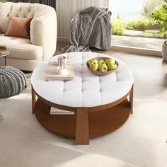 a living room filled with furniture and a white table topped with apples in front of a window