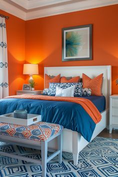 a bedroom with orange walls and blue bedding, white nightstands and an ottoman