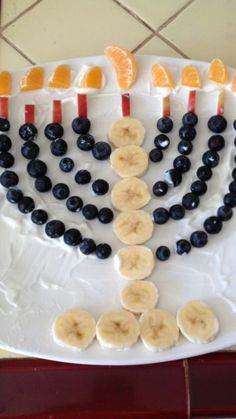 a white plate topped with sliced bananas and blueberries next to orange slices on a menorah