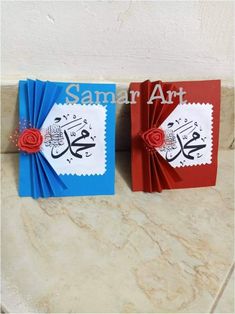 two folded greeting cards with the words samra art on them, one red and one blue