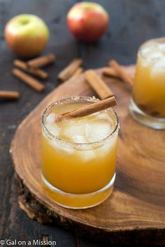 an apple cider cocktail with cinnamon garnish on the rim and apples in the background