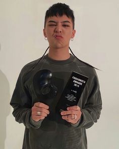 a young man holding up a black object in front of his face