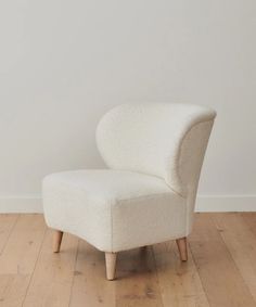 a white chair sitting on top of a hard wood floor next to a white wall