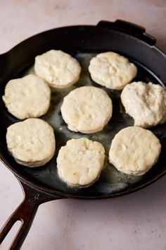 some biscuits are cooking in a skillet on the stove top with a spatula