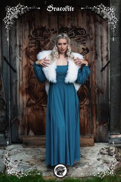 a woman in a long blue dress and fur stoler standing in front of a wooden door