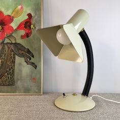 a lamp that is on top of a table next to a painting and some flowers