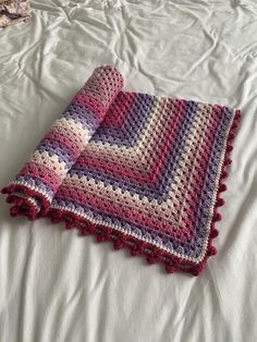 a crocheted blanket laying on top of a bed