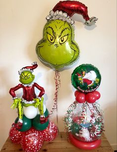 the grinch balloon is sitting next to another balloon with an elf hat on it