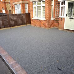 an empty driveway in front of a brick house