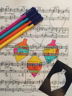 some crayons are laying on top of music sheets and pencils next to them