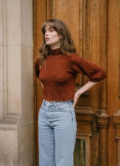 a woman standing in front of a door with her hands on her hips and looking off to the side