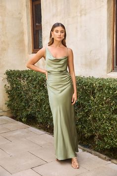 a woman standing in front of a building wearing a green dress