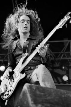 a man with long hair playing a guitar at a music festival in black and white