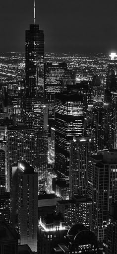 black and white photo of city at night with skyscrapers in the foreground, from above