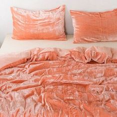 the bed is made up with peach colored sheets and pillowcases on top of it