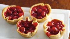 four mini pies with jelly filling on a white plate