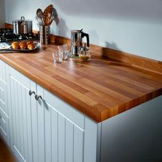 the kitchen counter is made of wood and has many utensils on it