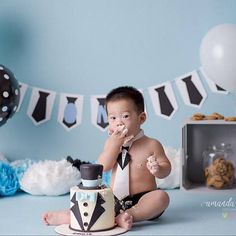 a baby boy sitting on the floor with his cake in front of him and eating it