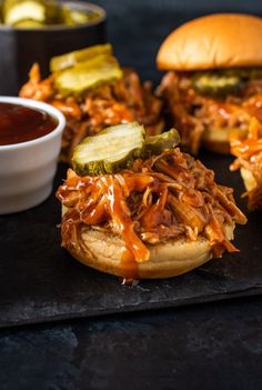 pulled pork sliders with pickles and barbecue sauce on a black slate platter