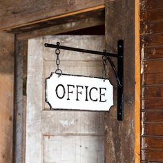 an office sign hanging from the side of a wooden door with chains attached to it