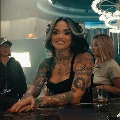 a woman with tattoos sitting at a bar