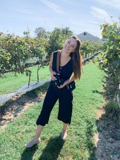 a woman standing in an apple orchard holding a camera