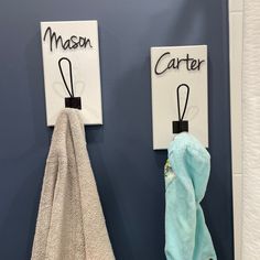 two towels are hanging on the wall next to each other with name tags attached to them