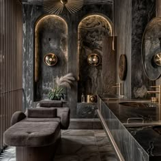 an elegant bathroom with black marble walls and gold accents, along with large round mirrors on the wall