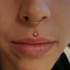 a close up of a person with a nose ring on their left side, wearing a gold nose chain