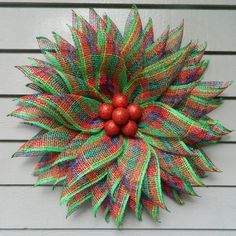 a green and red wreath hanging on the side of a building with two balls attached to it