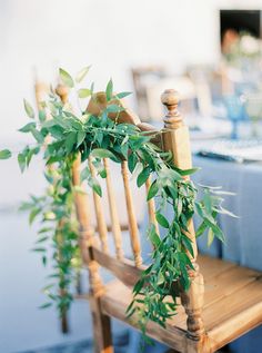 a wooden chair sitting next to a table covered in blue linens and greenery