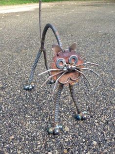 a metal cat sculpture sitting on top of a sidewalk