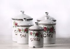 three white canisters with flowers painted on them