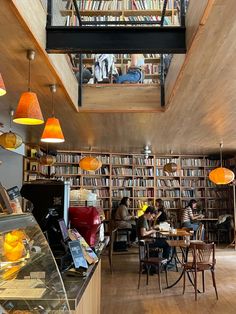 people sitting at tables in a library with lots of bookshelves on the walls