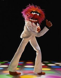 the muppet is dressed in all white and has his arms out as if he's dancing