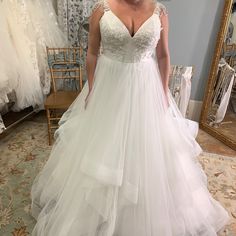 a woman standing in front of a mirror wearing a wedding dress