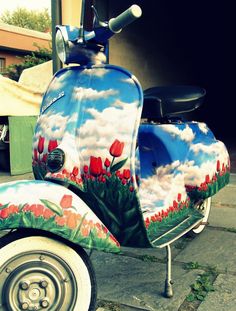 a scooter is painted with flowers and clouds