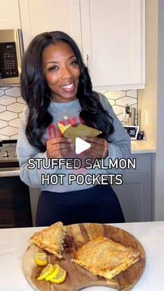 a woman holding a piece of food in front of her face with the caption, stuffed salmon hot pockets