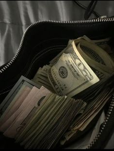 a purse filled with money sitting on top of a bed