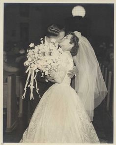 an old black and white photo of a bride kissing her groom in front of the alter