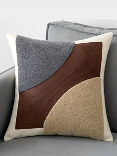 a gray couch with a brown and blue pillow sitting on it's back end